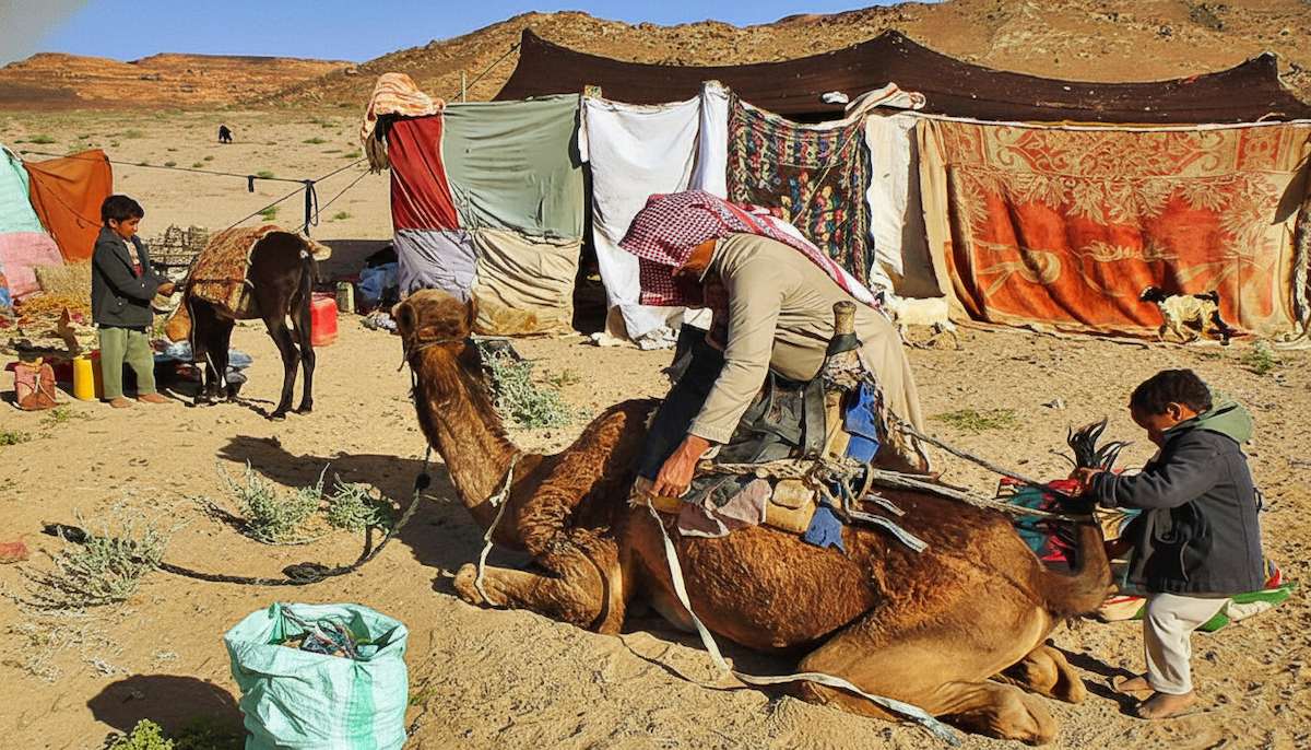 A vibrant scene depicting traditional Beduin life in the desert, with nomadic people, camels, and tents under a vast sky, showcasing their unique culture.